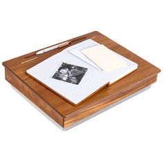 a wooden desk topped with an open notepad and pen