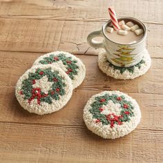 three crocheted coasters sitting on top of a wooden table next to a can