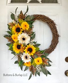 a wreath with sunflowers and greenery on the front door