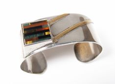 "Vintage Modernist Gemstone Inlay Square Sterling Silver 1\" Wide Cuff Bracelet Amazing modernist Sterling Silver Cuff Bracelet. Stunning design and multi inlay gemstone square! Amber, Carnelian, Malachite, Black Onyx...There are diagonal lines of separately applied gold. An extremely unique design you do not see every day. Measures 1\" wide. Beautiful piece! Inner circumference is approx 6-1/2\". Marked \"Sterling\" on the inside. We do not see a makers mark. In very good condition. May require Modern Multicolor Cuff Bangle Bracelet, Modern Multicolor Bangle Cuff Bracelet, Modern Multicolor Rectangular Jewelry, Modern Rectangular Jewelry With Polished Finish, Modernist Cuff Jewelry For Gift, Unique Rectangular Inlay Jewelry, Modernist Cuff Jewelry With Polished Finish, Modernist Polished Cuff Jewelry, Modern Rectangular Bracelet With Polished Finish