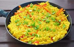 a pan filled with rice and vegetables on top of a wooden table