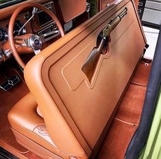 the interior of an old car with brown leather and wood trims, including steering wheel