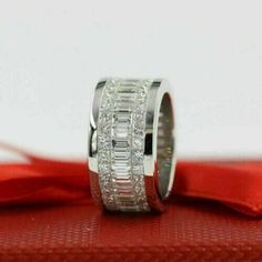 a wedding ring with baguetts on it sitting on top of a red box