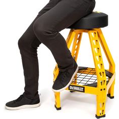 a man sitting on top of a yellow step stool with his feet propped against the seat