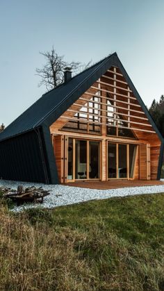 a large wooden house sitting on top of a lush green field next to a forest