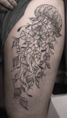 a woman's thigh with flowers and leaves on it