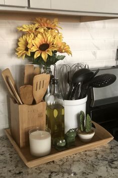 sunflowers and kitchen utensils are on a tray in the kitchen counter