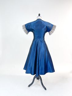 "A fabulous vintage dress from the 1950s! Crisp rayon 'sharkskin' taffeta in the prettiest shade of shimmering blue. Sweetheart bodice tightly fitted through waist and full, flirty a-line skirt. Sweetheart neckline with pale pinky-nudedetail with finely pleated tulle overlay. Matching copped jacketed with small collar, plunging neckline and covered button closure. Dress can be worn strapless-straps button on inside of front bodice so they can be tucked away if not needed. No labels present. Meta Blue A-line Vintage Dress For Party, Blue Taffeta Evening Dress For Party, Blue Fitted Taffeta Evening Dress, Fitted Blue Vintage Dress For Evening, Blue Vintage Evening Dress, Vintage Blue Evening Dress For Party, Blue Vintage Dress For Party, Blue Vintage Party Dress, 1950s Blue Evening Dress