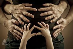 several hands on top of each other in front of a black background with an image of two adults and one child