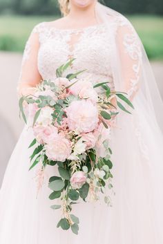 a bride holds her bouquet in front of the camera while wearing a wedding dress and veil