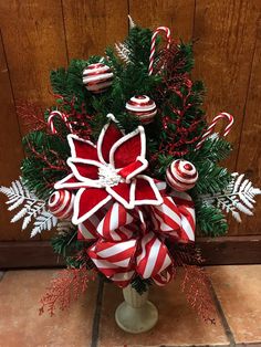 a vase filled with candy canes and decorations on top of a tile floor next to a wooden wall