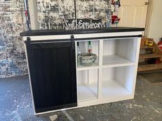 a white cabinet with black doors and shelves in a room that is being renovated into a bar