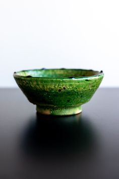 a green bowl sitting on top of a black table