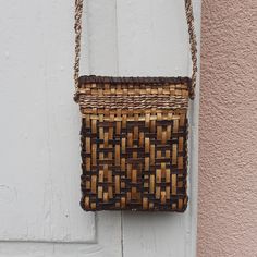 a woven purse hanging on the side of a white door with a pink wall behind it