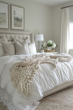 a white bed sitting in a bedroom next to two pictures on the wall above it