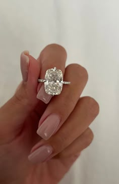 a woman's hand holding a ring with a large diamond on the middle of it