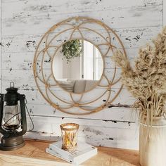 a round mirror sitting on top of a wooden table next to a vase with flowers