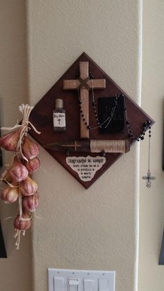 a cross hanging on the side of a wall next to a light switch and some flowers