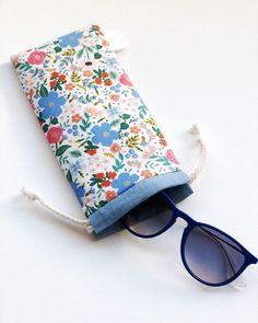 a pair of sunglasses sitting on top of a flowered pouch with blue glasses in it