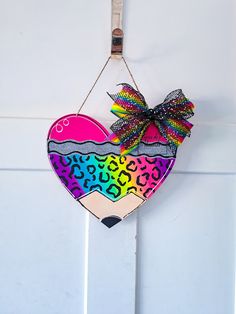 a heart shaped ornament hanging on a wall with a bow and leopard print