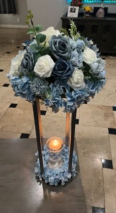 a vase filled with blue and white flowers sitting on top of a table next to a candle