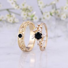 two gold wedding rings with black stones and diamonds on the sides, sitting next to each other