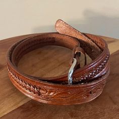 Decorative brown leather belt with hand-tooled details and a simple silver metal buckle. The belt measures 42" and is a marked size 34, made in Mexico. There are 5 belt holes and there is light wear on the inside of the belt near the belt holes. Adjustable Hand-tooled Leather Belt, Adjustable Hand Tooled Brown Belt, Classic Adjustable Hand Tooled Belt, Classic Adjustable Hand-tooled Belt, Adjustable Hand-tooled Brown Belt, Classic Adjustable Embroidered Belt, Adjustable Leather Concho Belt, Traditional Leather Belt Buckle, Adjustable, Brown Hand Tooled Adjustable Belts And Suspenders