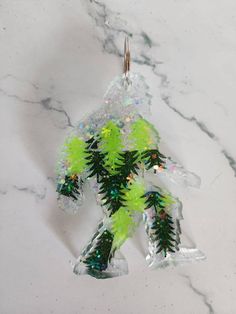 a glass ornament with green and white decorations on it's side, sitting on a marble surface