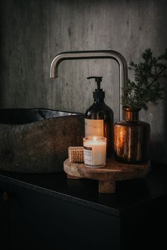 a candle and soap dispenser sitting on a wooden shelf next to a sink