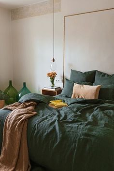 a bed with green sheets and pillows in a room