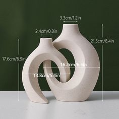 a white vase sitting on top of a table next to a blackboard with measurements