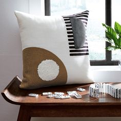 a wooden table topped with pillows next to a vase filled with flowers and dominos