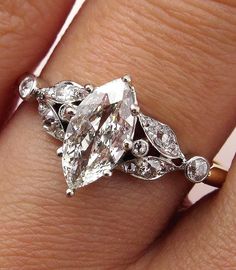 a woman's hand with a diamond ring on top of her finger and an engagement band