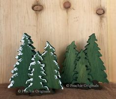 three wooden christmas trees sitting next to each other on top of a table in front of a wood panel