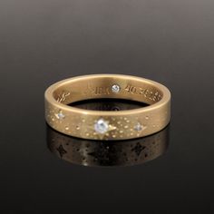 a gold wedding ring with three diamonds on the inside and outside, sitting on a black surface