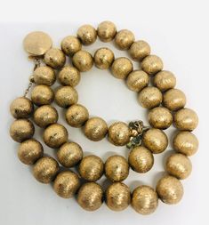 Beautiful vintage textured gold tone/plated beaded ball necklace. Lovely detailed texture to gold tone/plated metal beads strung on chain. Has large secure push in clasp. Not lightweight but comfortable to wear. Beads measure 3/8 inch across and total length is 17 inches. Excellent vintage condition with minimal age appropriate wear. Could use a polish but as always leave that up to buyer. Beautiful beaded necklace!! Luxury Vintage Gold Beads, Vintage Gold Polished Beads, Vintage Polished Gold Beads, Large Gold Beads For Costume Jewelry, Gold Metal Beaded Necklaces With Large Beads, Gold Metal Beaded Necklace With Large Beads, Gold Brass Beaded Necklace With Round Beads, Vintage Large Gold Beads, Gold Beaded Necklace With Large Metal Beads