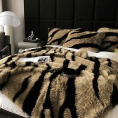 a bed with black and white fur on it's comforter in a bedroom