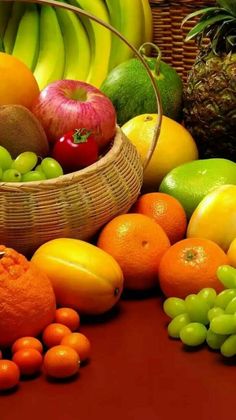 a basket filled with lots of different types of fruit next to bananas and oranges