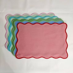 pink and blue placemats with scalloped edges on white tablecloth background