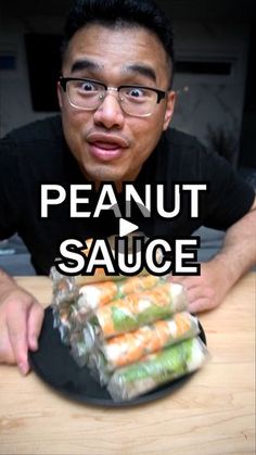 a man sitting at a table with food in front of him that says peanut sauce