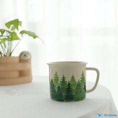 a coffee cup sitting on top of a table next to a potted green plant