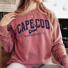 The Comfort Colors Cape Cod Sweatshirt is the perfect Cape Cod gift for beach lovers and preppy teens. With its beachy vibes and cozy feel, this sweatshirt is a must-have for any VSCO girl. The stylish pullover features a classic Cape Cod design, making it a fashionable statement piece. Whether you're gifting it to a friend or treating yourself, this sweatshirt embodies the laid-back spirit of Cape Cod. Stay warm and stylish with this beachy sweatshirt. 🖤 For oversized order 1-3 sizes up, refer to listing photos for size guide 🖤 Comfort Colors 1566 Preppy Cotton Tops With Letter Print, Preppy Crew Neck Top For College, Pink Collegiate Cotton Tops, Preppy Crew Neck Top With Graphic Print, Preppy Graphic Print Crew Neck Top, Casual Pink Pre-shrunk Sweatshirt, Gold Cape Cod Bracelet, Beachy Sweatshirt, Cape Cod Design