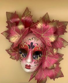 This original, hand painted venetian mask displays a woman's face with striking, vibrant colors, including gold, red, black and a shade of white. It showcases a uniquely intricate painted design on the face and is embellished with gold and red magnolia leaves as the headdress. It has a black satin tie in the back for easy wear and a small fabric hook for display. A perfect purchase just in time to embrace the Halloween spirit or to add flair for a masquerade ball. This venetian artisan piece is Red Magnolia, Mask Art, Venetian Mask, Magnolia Leaves, Gold And Red, Masks Art, Masquerade Ball, Halloween Spirit, Shades Of White