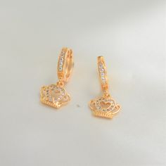 Dangle in regal delight with our Crown Earrings, a masterpiece of elegance and charm. Embrace timeless sophistication and radiate confidence with every sway. The crown symbol jewel represents glory, power, immortality, royalty and sovereignty. 14K Gold Plating Suitable for daily wear Light weight Hypoallergenic Nickel free Waterproof Tarnish Resistant Maintenance Tips: To keep our products in top-notch condition, we recommend avoiding contact with substances such as perfumes, hairsprays, and lot