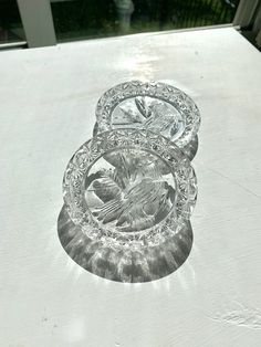 three clear glass plates sitting on top of a white tablecloth covered table with an image of a bird in the center