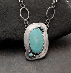 Beautiful Kingman Turquoise Stone with Handmade, One-of-a-Kind Sterling Silver Chain.  Oh, the color of this stone  Tons of time and love went into this piece featuring a lovely, large Kingman turquoise stone set in a scalloped, layered setting, with the added detail of Carico Lake turquoise and silver ball embellishments. I added even more love by texturing the edges of the layered setting and making every link of the matching, textured, handmade chain.  Truly unique and definitely one-of-a-kind.  Details: ~    Pendant measures 1 5/8" long & slightly more than 1" wide ~   The large stone is from the Kingman, AZ mines and has been cut & stabilized by an AZ lapidarist/jeweler. ~    Two small stones are Carico Lake from Lander County, Nevada and have been cut by an American lapidarist. ~ Turquoise Jewelry With Large Round Stone Pendant, Turquoise Round Pendant With Large Stone, Southwestern Hand Forged Turquoise Jewelry, Southwestern Style Hand Forged Turquoise Jewelry, Artisan Turquoise Necklace With Large Stone, Unique Turquoise Necklace With Large Stone, Turquoise Gemstone Oval Pendant Jewelry, Artisan Turquoise Necklace, Hand Forged Turquoise Pendant Necklace