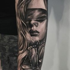 a woman with a blindfolded eye and scale of justice tattoo on her arm