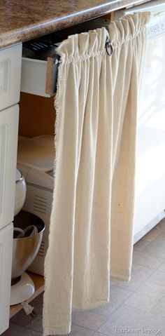 an open cabinet door with curtains hanging from it