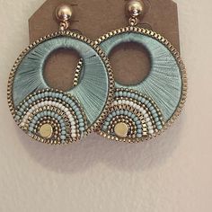 a pair of blue and white earrings hanging from a hook on top of a wall