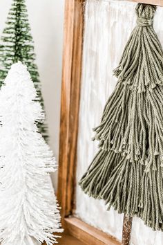 two small christmas trees sitting next to each other on a wooden shelf in front of a mirror